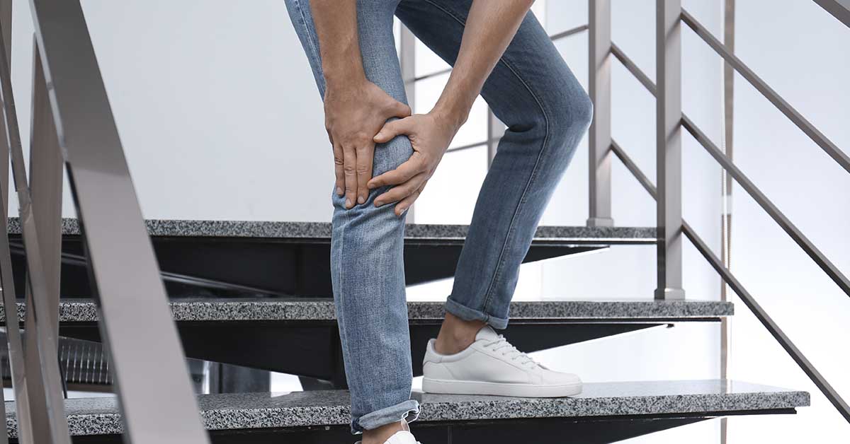 Homem com a mão no joelho enquanto desce um lance de escadas