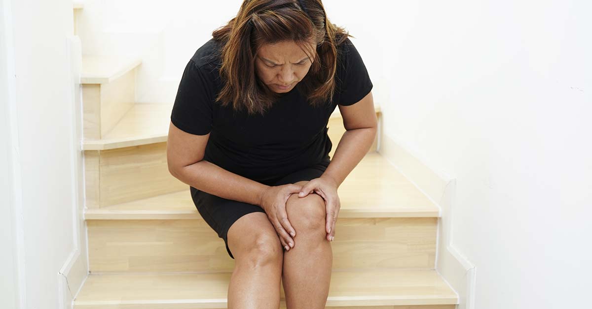 Mulher sentada na escada com a mão no joelho
